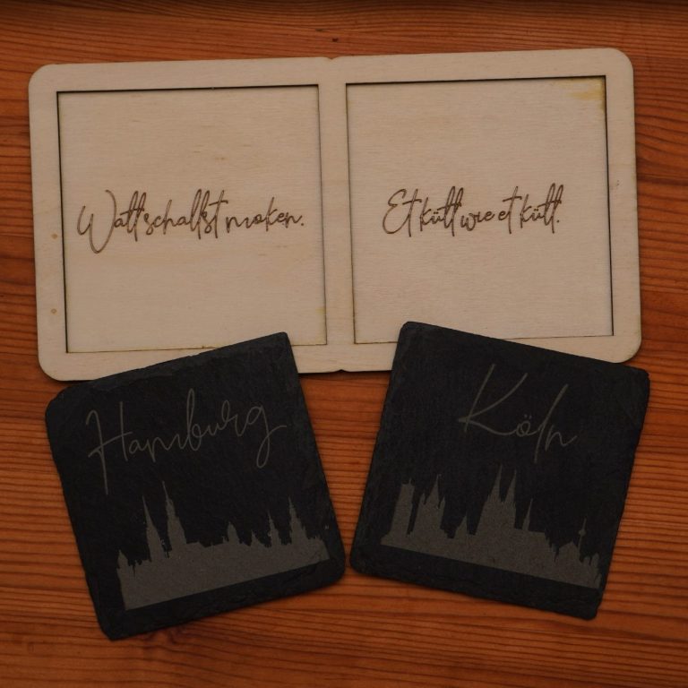 Untersetzerset individuell graviert Zwei Getränkeuntersetzer mit gelaserten Beschriftungen und stilisierten Stadtansichten.